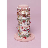 Stack of assorted colorful beads and holiday-themed charms for kids displayed on a stand, Holiday Bracelet.