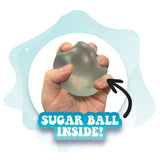 Hand squeezing a soft translucent stress toy revealing a gel-like sugar ball inside for calming sensory relief.