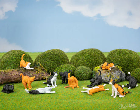 Itty Bitty Cats small vinyl cat figurines in various poses and colors displayed on grass with greenery background.