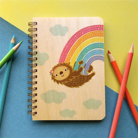 Wood Notebook | Rainbow Sloth with eco-friendly birch wood cover featuring a playful sloth and rainbow design, pocket-sized spiral bound.