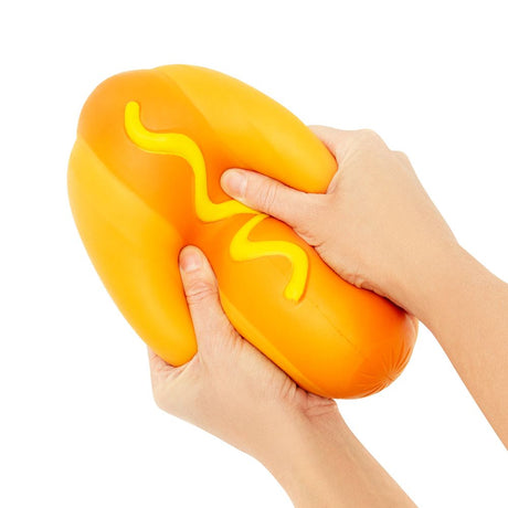 The Big Squij Hot Dog orange squishy toy with yellow mustard detail held in hands