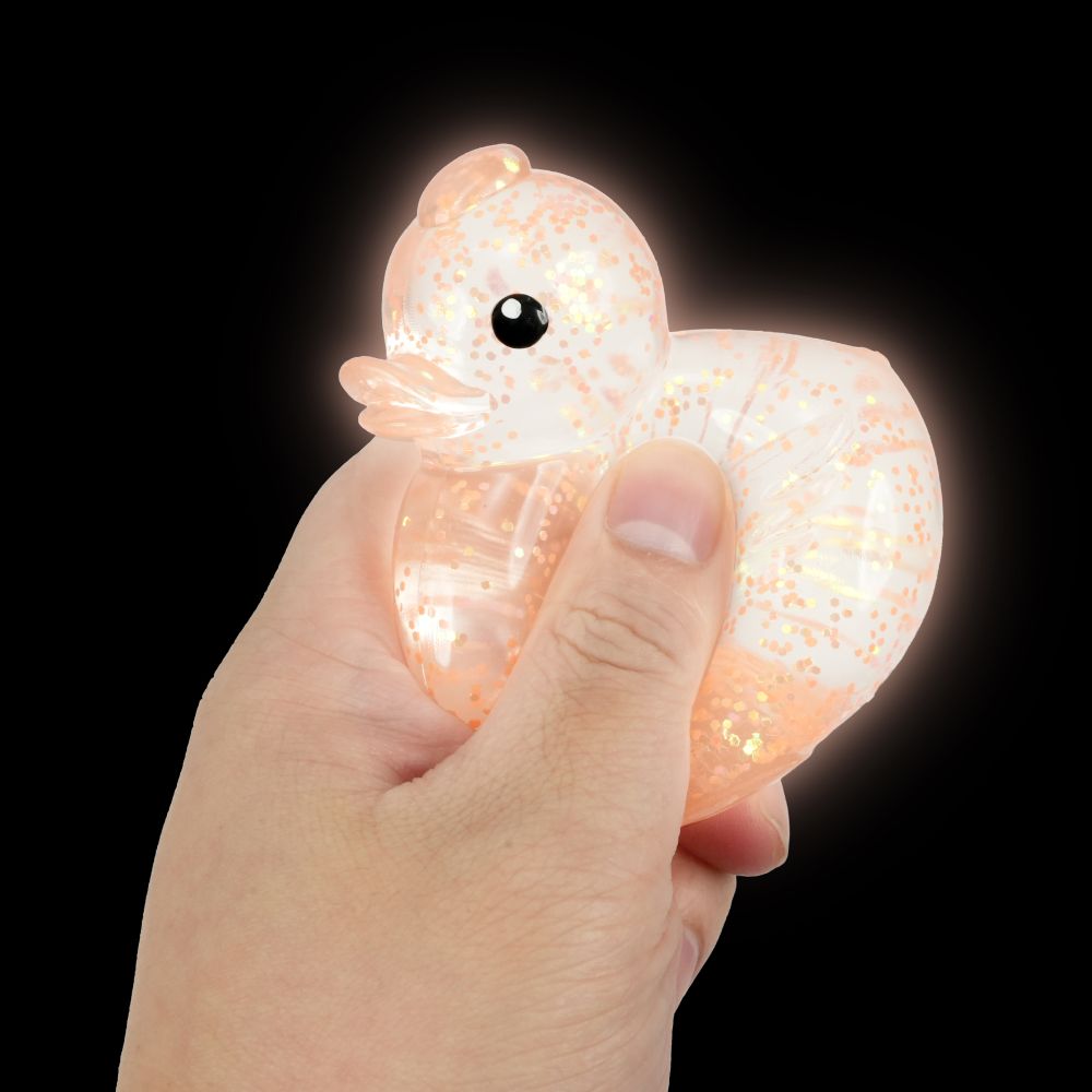 Hand holding a glowing translucent octopus-shaped toy against a black background