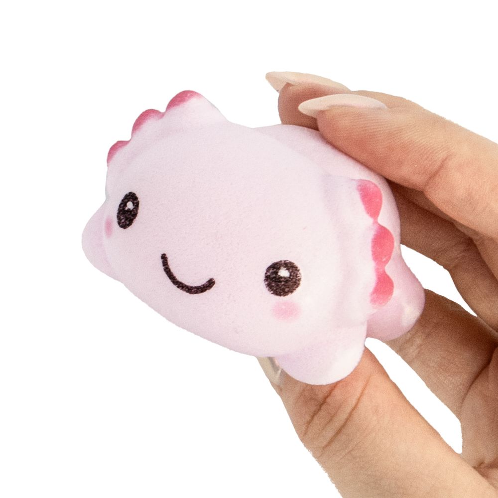 Hand holding a small pink Grow Axolotl toy with smiling face, showcasing its cute and friendly design.