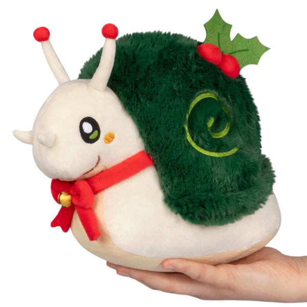 Plush white snail with large eyes, festive green fuzzy shell decorated with holly leaves and red berries, red scarf with bell