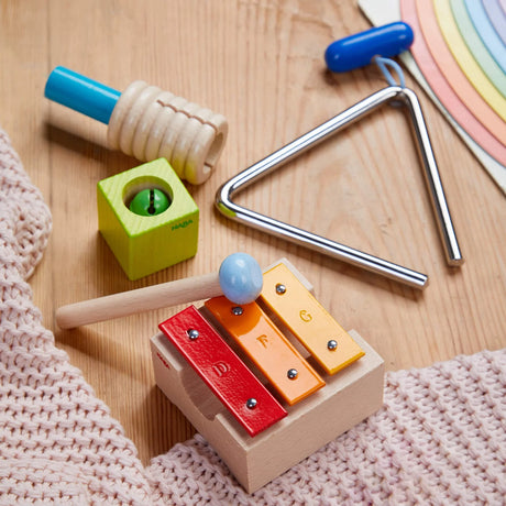 Musical Sounds Musical Joy Play Set with triangle, guiro, jingle block, mini metallophone, and mallet on wooden surface.