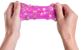 Hands pulling translucent pink slime with embedded miniature fruit slices on a white background