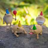 Party Frogs set of four soft vinyl rain frogs wearing party hats and accessories on a rock outdoors.