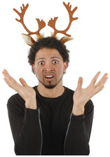 Man wearing Reindeer Antlers headband with brown fuzzy antlers and ears, looking confused and festive.
