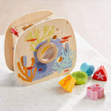 Wooden underwater shape sorter with sea creature blocks including turtle, starfish, crab, and seahorse on a soft surface