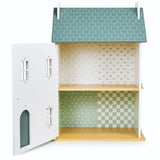 Open wooden dollhouse with three rooms featuring patterned wallpaper and a green shingled roof