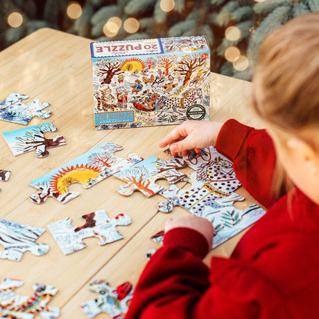 Child assembling a colorful 20-piece winter sleigh ride puzzle with detailed animal illustrations on a wooden table.