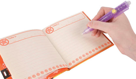 Hand holding the 2-in-1 Invisible Writer pen writing in a notebook with visible blue ink on pages.