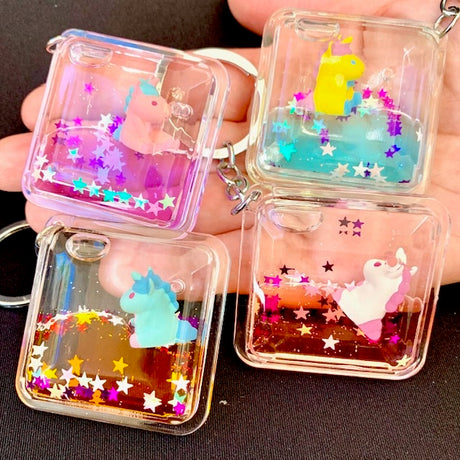 Floating Unicorn KeyChain with colorful glitter and assorted unicorn designs in clear square casing.