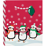 Gift Bag Large North Pole Characters with playful penguins ice skating, snowflakes, white pom-pom handles, and Christmas-light hang tag.