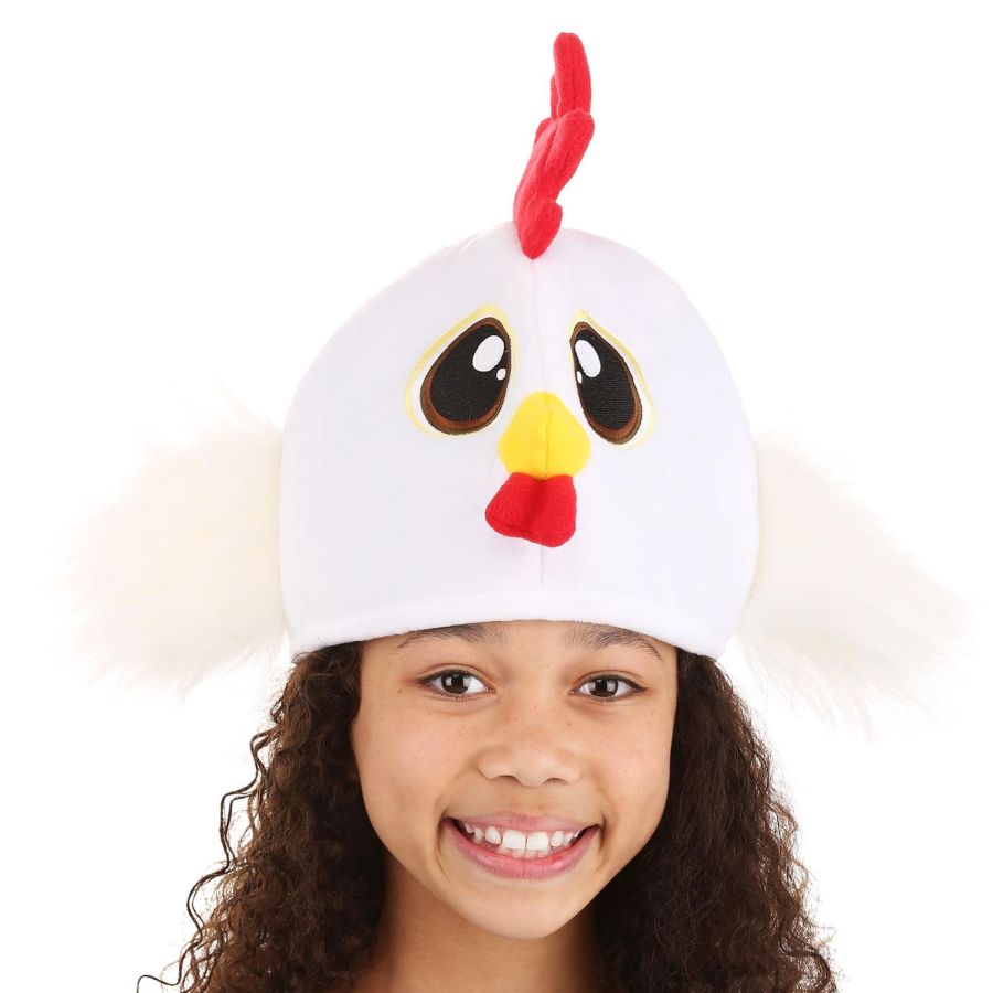Smiling girl wearing the Chicken Hat with big embroidered eyes, stuffed beak, and fluffy wings on white background.