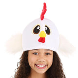 Smiling girl wearing the Chicken Hat with big embroidered eyes, stuffed beak, and fluffy wings on white background.