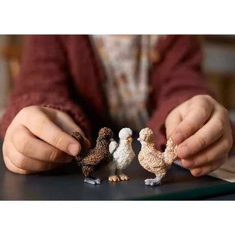 Child holding three detailed chicken figurines including two Polish and one Silkie in the Chicken Friends set.