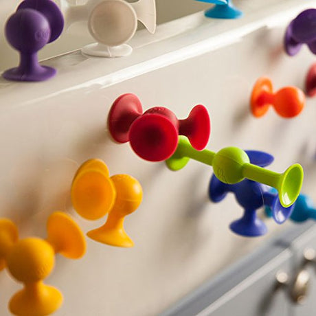 Colorful Squigz suction toys connected to a smooth surface, showcasing flexible, creative play with the Squigz product.