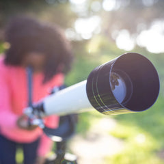 Omega Refractor Telescope focused on outdoors with child using it for space exploration and sky observation.