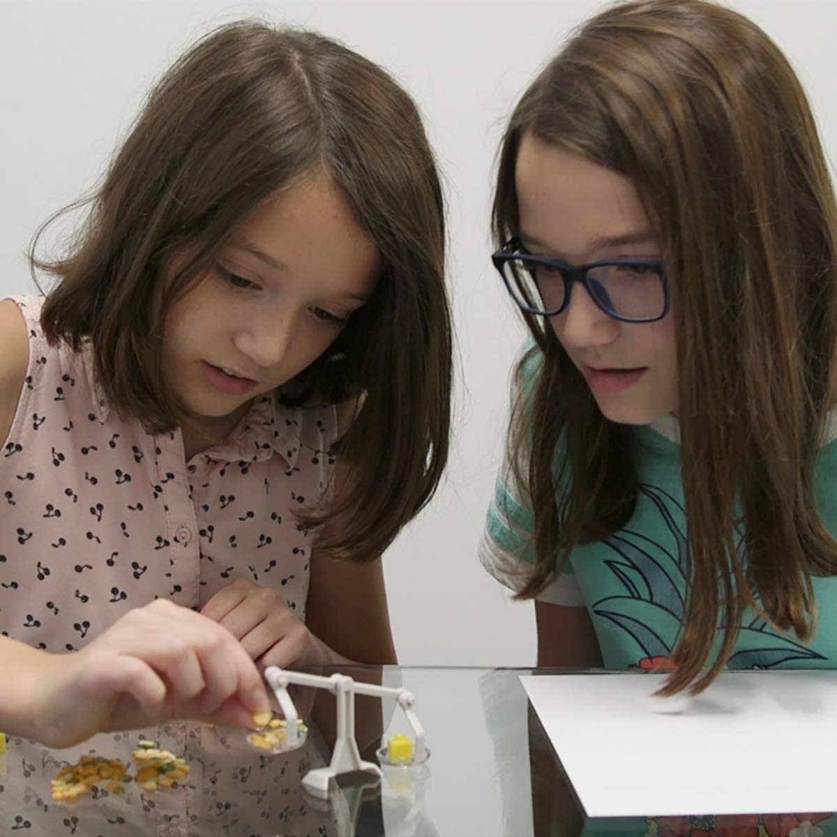 Two girls using a balance scale to explore science with Tiny Tools Tiny Science set for kids aged 8 and up.