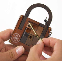 Close-up of hands solving the wooden Einstein Lock Puzzle with a brass key, a challenging brainteaser for ages 8+