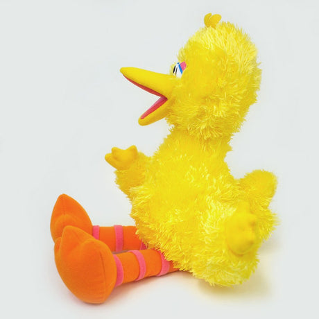 Big Bird plush sitting sideways showing soft yellow fur and orange striped legs, perfect for cuddling and decor.