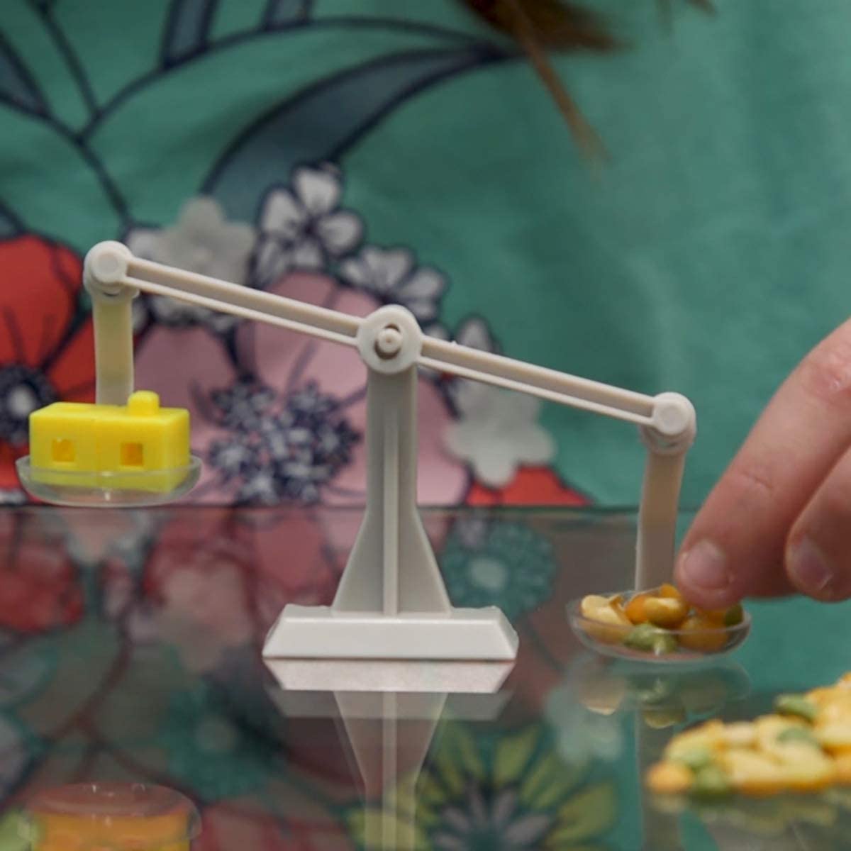 Tiny Tools Tiny Science miniature balance scale with weights used in a kid’s hands for precision science experiments.