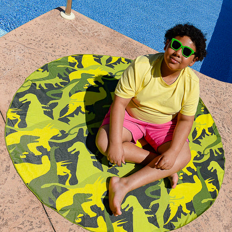 Child sitting on a vibrant Towel Dino Camo round towel by the pool, perfect for beach or picnic use.