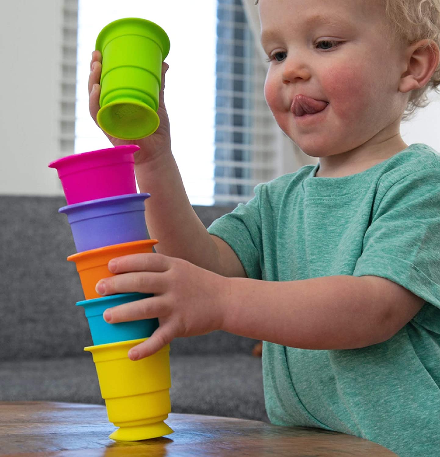 Young child stacking colorful silicone cups with suction bases, playing with Suction Kupz for creative fun.