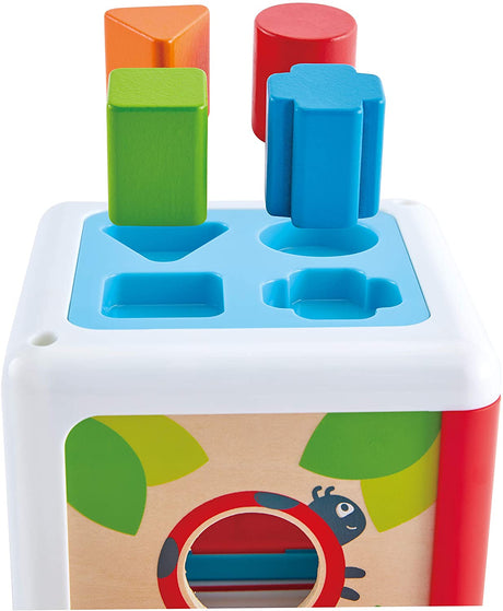 Shape Sorting Box with colorful wooden shapes matching holes on top of a white cube toy for toddlers.
