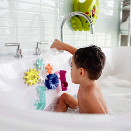 Child playing with colorful spinning COGS Water Gears attached to bath wall during bath time fun.