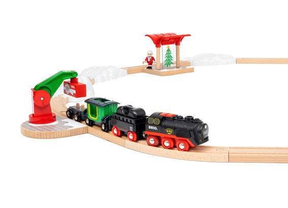 Steaming Christmas Train Set with battery-operated engine, snowy tracks, North Pole station, and Santa Claus figure on wooden train tracks.