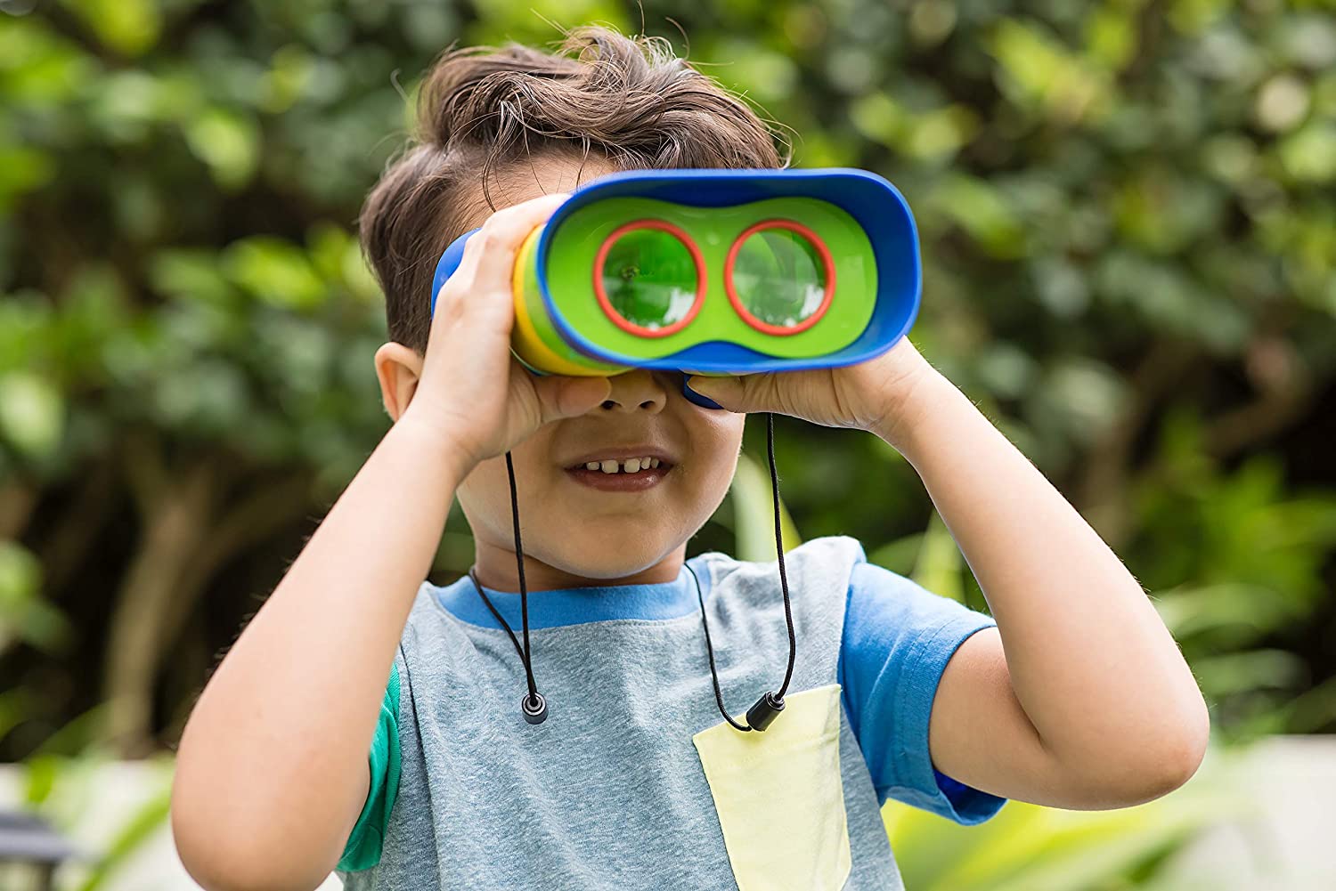 Child using Kidnoculars Binoculars with enlarged eyepieces and breakaway neck strap for outdoor exploration.