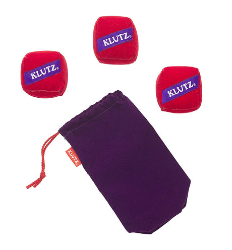 Juggling for the Complete Klutz with three red beanbags and purple drawstring pouch for beginner juggling practice.