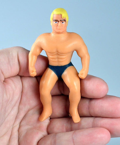 Hand holding the World's Smallest Stretch Armstrong toy showing its compact and muscular design.