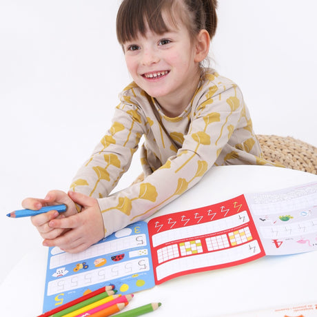 A smiling child using the Loong Numbers Activity Book with colorful number tracing and writing exercises.