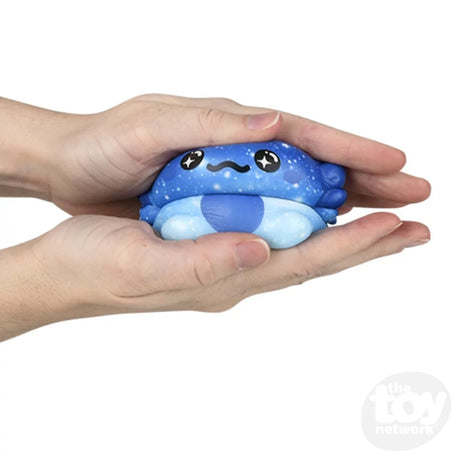 Hands squeezing a blue Squishy Axolotl 4in toy showing its stretchable, soft texture and cute design.