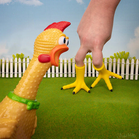 Chicken Foot soft vinyl finger puppet worn on fingers with a toy chicken in the background on grass.