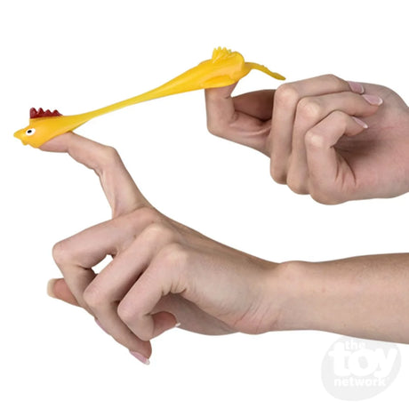Hands stretching and launching a yellow Slingshot Chicken toy, showing its elastic and playful design.