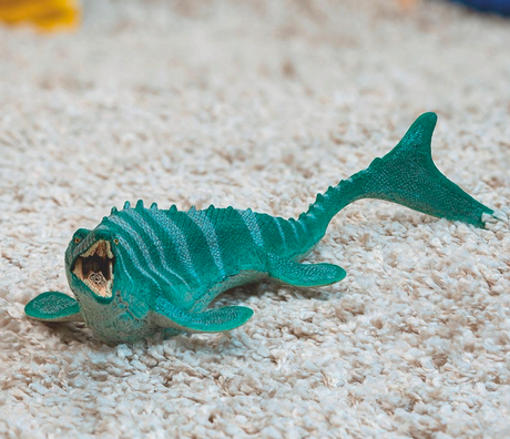 Mosasaurus toy with movable jaw and pointy teeth, designed with fins and tail fin for aquatic adaptation.