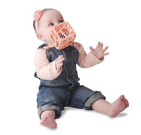 Baby chewing on the Chew Cube | Peachy Pink teether with textured edges and rattle for sensory stimulation.