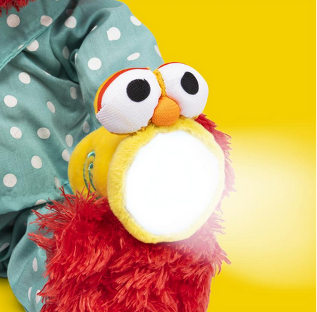 Bedtime Elmo plush in blue polka-dot pajamas holding glowing flashlight with soft LED light for kids.
