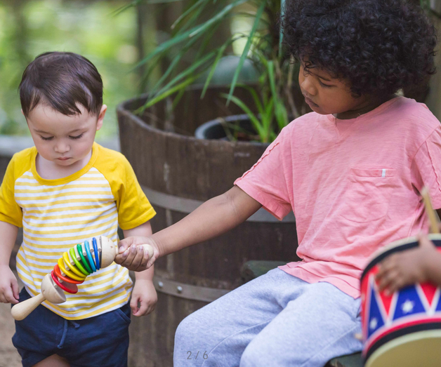 Two children playing with the colorful Clatter toy, creating click-clack sounds with alternating hand motions.