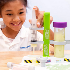 Child using syringe tool to test slime viscosity in the Ooze Labs Alien Slime Lab kit chemistry set.