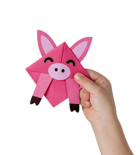 Hand holding a pink pig corner creature bookmark made with origami from the Corner Creature Bookmarks set.