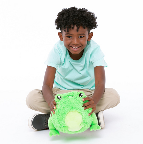 Smiling child holding a soft, green Frog Mini plush toy, perfect for cuddling and playtime fun.