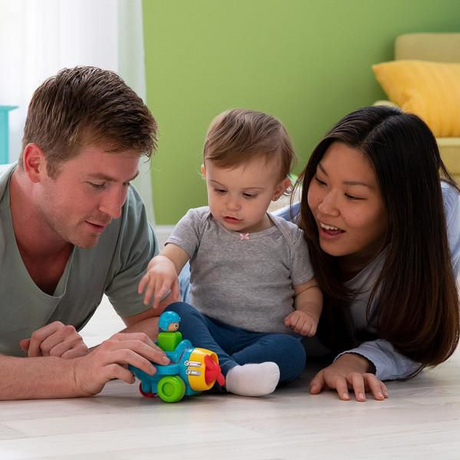 Baby playing on the floor with parents using the Press & Go Airplane toy encouraging fine motor skills.