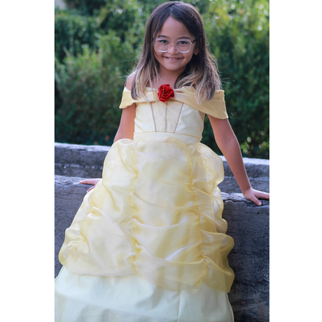 Girl wearing Belle Boutique Gown Size 5-6 in pale yellow with off-the-shoulder straps and red rose detail.