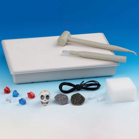 I Dig It Pirate Treasure kit with plaster block, hammer, chisel, plastic gems, coins, skull bead, and string for kids.