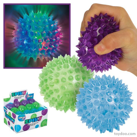 Spikey LightUp Ball glowing blue, green, and purple with textured spikes, handheld and shown in display box.